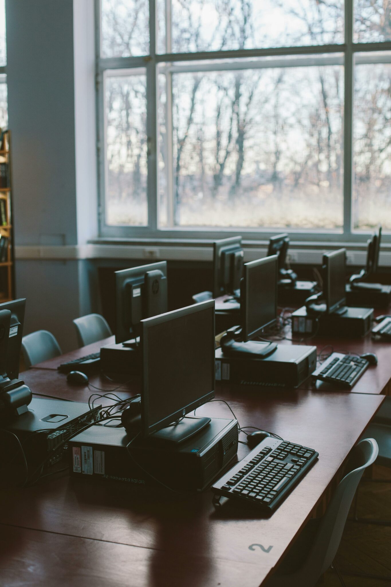 Spacious computer lab with rows of monitors and keyboards in a sunlit room.