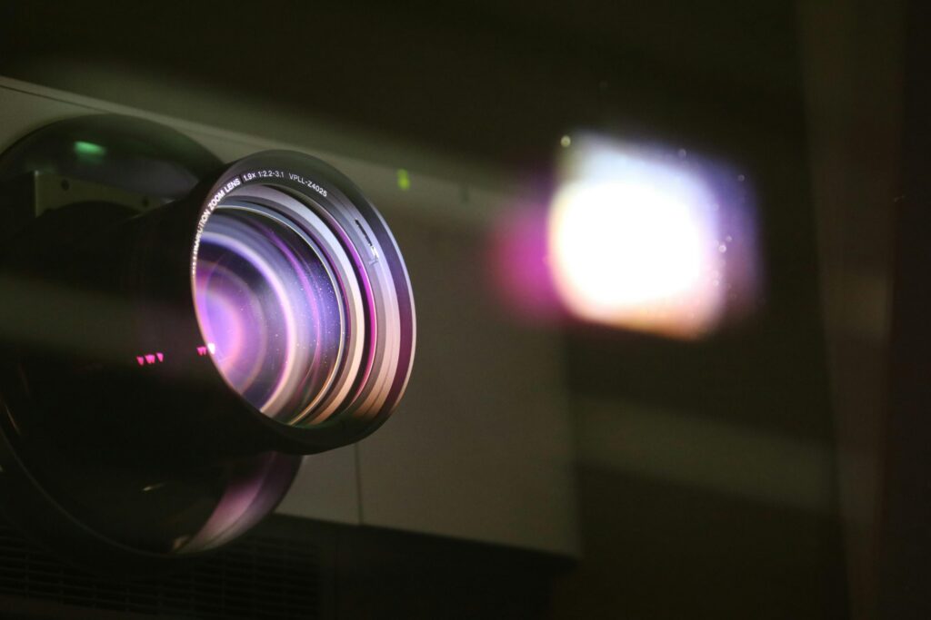 Close-up view of a projector lens with light reflections, highlighting optics and technology.